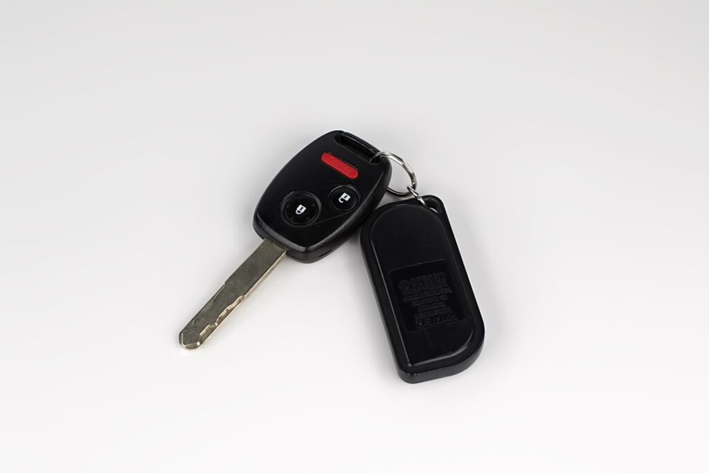 A close-up of a car key fob and metal key on a plain surface