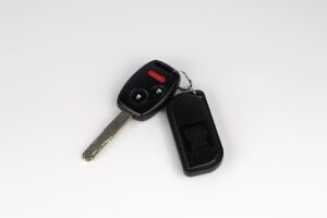 A close-up of a car key fob and metal key on a plain surface