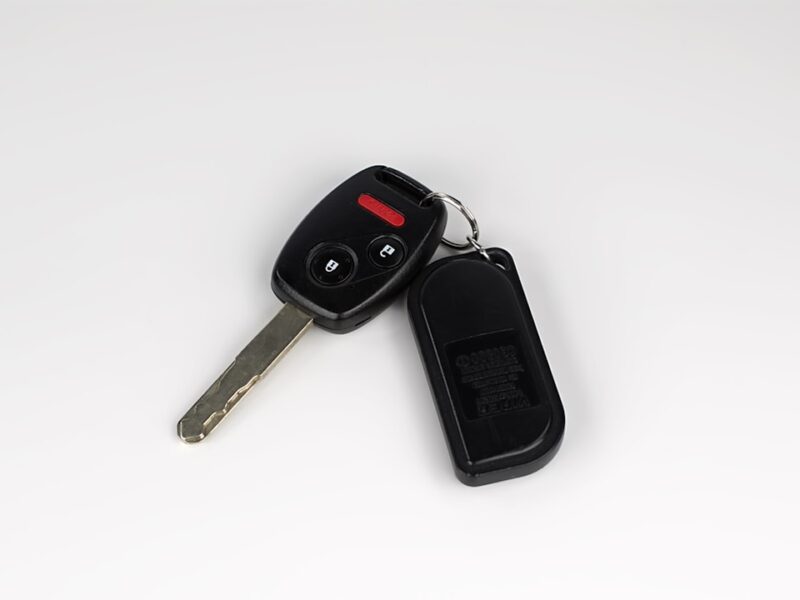 A close-up of a car key fob and metal key on a plain surface